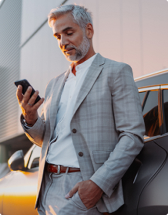 Starszy mężczyzna używający telefonu, oparty o auto