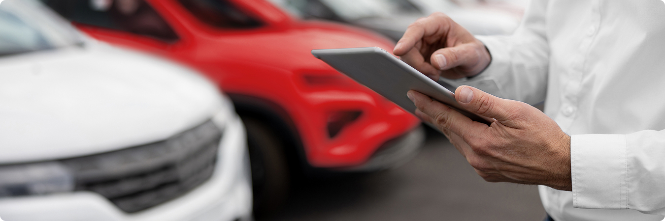 Mężczyzna korzystający z tabletu na tle salonu samochodowego