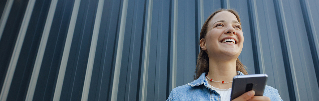 Uśmiechnięta kobieta z telefonem w ręku.