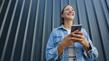Uśmiechnięta kobieta z telefonem w ręku.