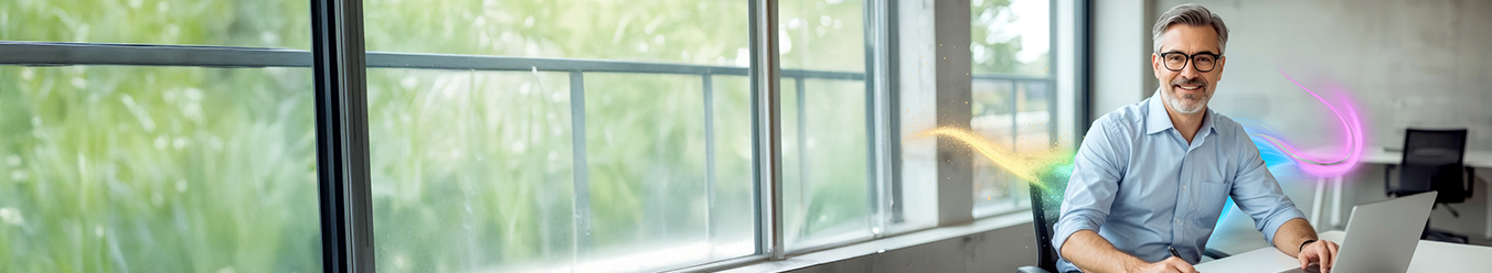 Siedzący przy biurku z laptopem uśmiechnięty mężczyzna w biurze.