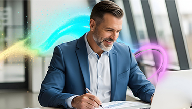 Uśmiechnięty mężczyzna w garniturze siedzi w biurze i uzupełnia dokumenty