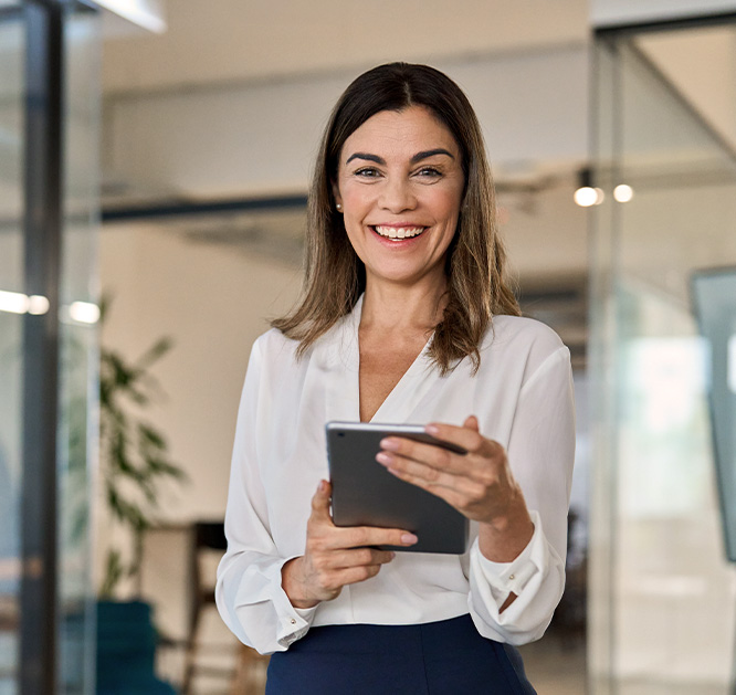 Obraz zawierający uśmiechniętą kobietę z tabletem w dłoniach. Znajduje się z nowoczesnym biurze