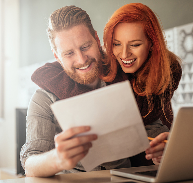 Uśmiechnięta kobieta i uśmiechnięty mężczyzna czytają dokument.