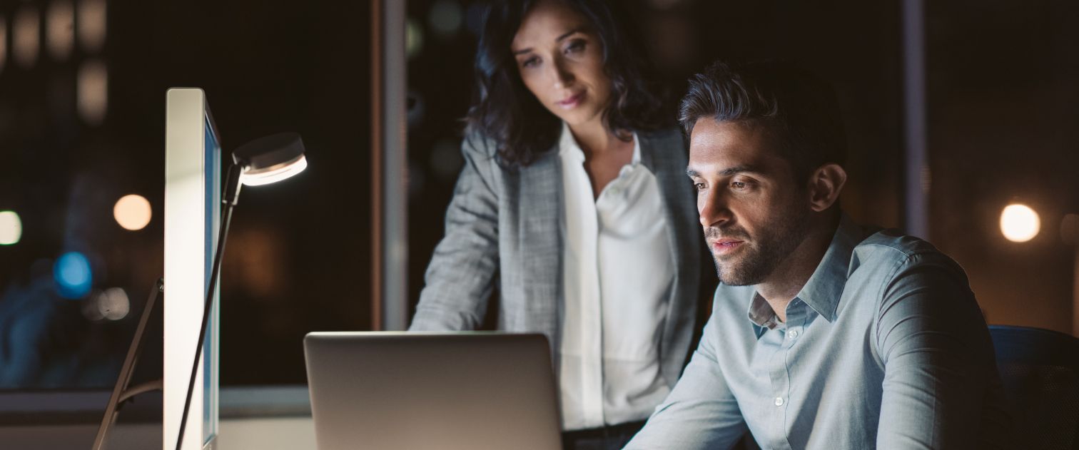 Mężczyzna i kobieta siedzą w biurze, patrząc w ekran monitora