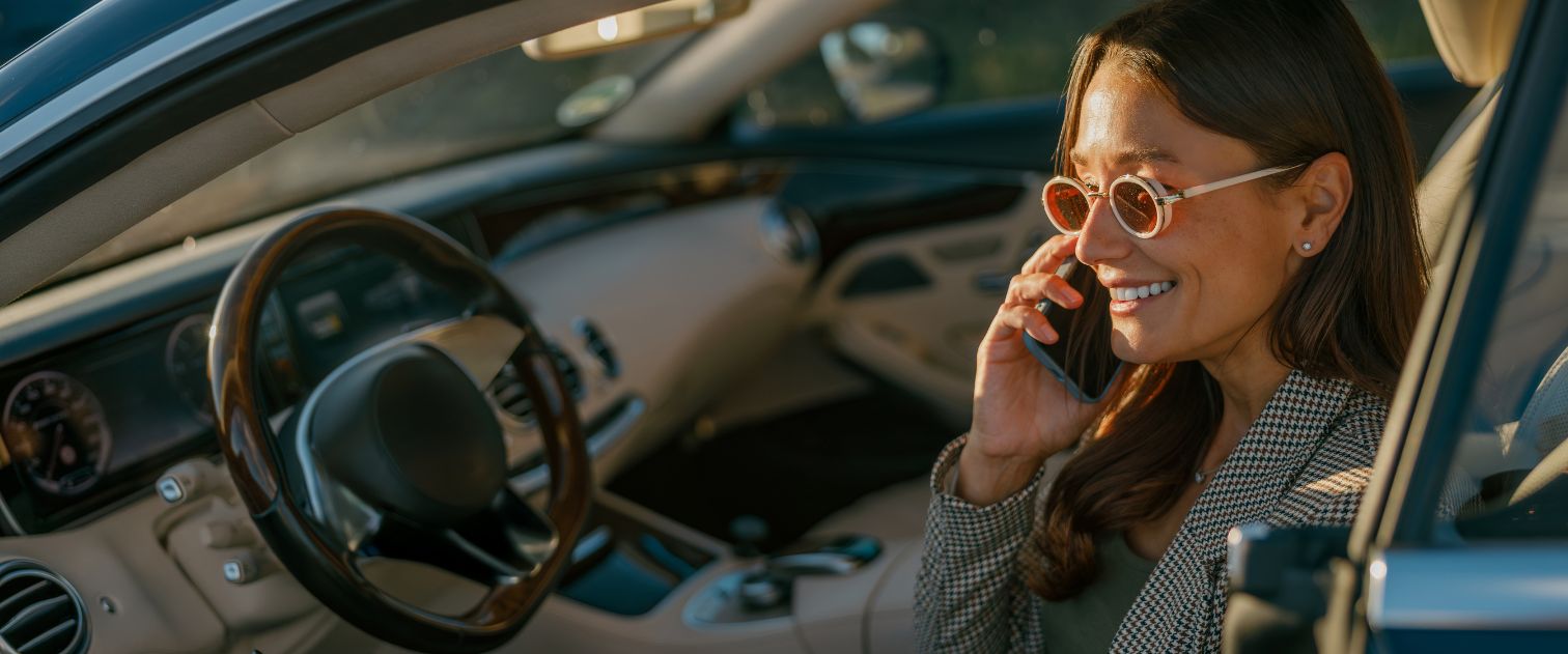 Kobieta siedzi w aucie i rozmawia przez telefon
