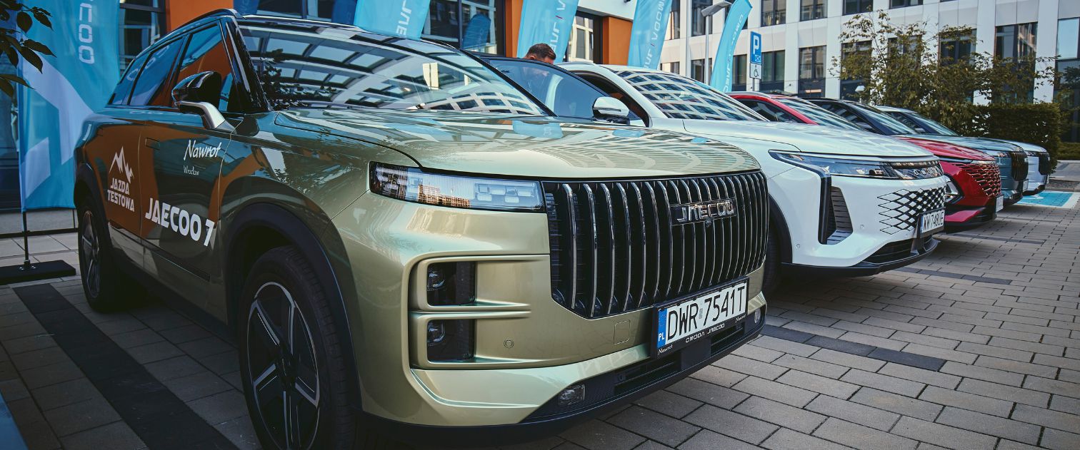 Samochody marki Jaecoo i OMODA. Ustawione na parkingu na pierwszym planie auto marki JAECOO w kolorze zielonym, SUV.