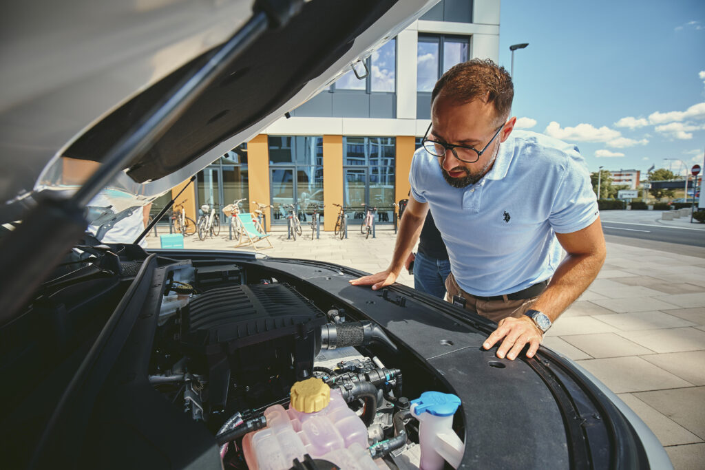 Mężczyzna zagląda pod maskę samochodu OMODA 9