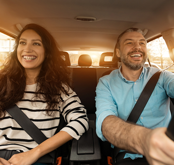 Uśmiechnięta kobieta i mężczyzna jadąca samochodem