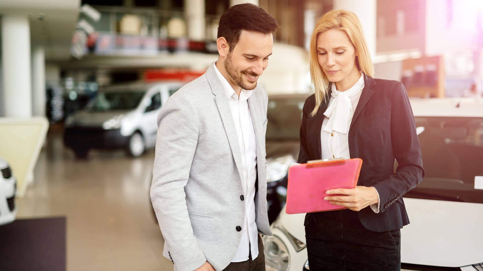 Kobieta i mężczyzna w salonie samochodowym. Kobieta doradczyni klienta przedstawia klientowi ofertę.