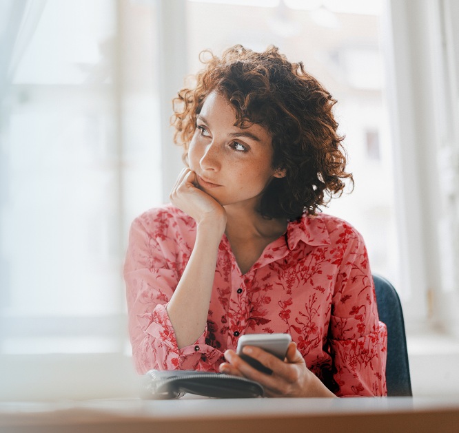Zamyślona kobieta z telefonem w ręku