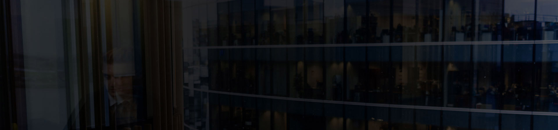 przyciemnione odbicie pracownika w szybie biurowca